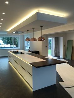 a kitchen with an island in the middle and lights on above it, along with large windows