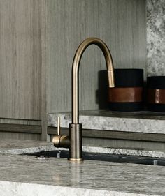 a kitchen sink with a brass faucet and marble counter top in the background