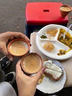 two people sitting at a table with plates of food and cups of coffee in front of them