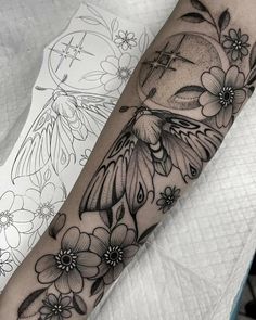 a black and white tattoo with flowers on the arm, which has a clock in it