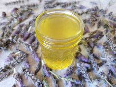 a jar filled with yellow liquid sitting on top of a table covered in lavender flowers