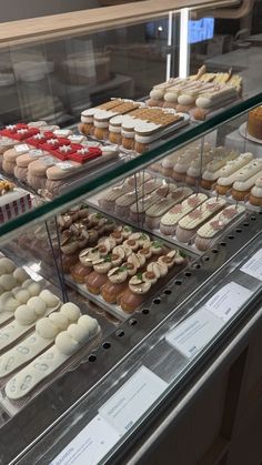 a display case filled with lots of different types of cakes and pastries on top of glass shelves