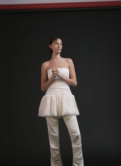 The Satine Top is crafted of our medium weight satin fabric in timeless off-white color. This sleek silhouette features a strapless neckline with bone corsetry and a hook-and-eye panel at the back for structure and support. Featuring a playful drop waist balloon piece with a pin-tucked ruffle detailing and gathering. Style Tip: Pair with trousers and mules for a cool look. DESCRIPTION -The fit of this skirt runs true to size -Strapless neckline -hook-and-eye panel closure at the back -drop waist balloon detail -Fully Lined -Dry Clean -100% Silk Satin Model is 5' 9' and is wearing a size Small Made in New York Strapless Neckline, Off White Color, Pin Tucks, Drop Waist, Satin Fabric, Silk Satin, Medium Weight, White Color, Strapless Top