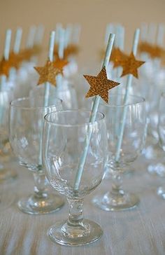 there are many wine glasses with straws in them and gold stars on the top