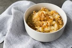 a white bowl filled with macaroni and cheese on top of a blue towel