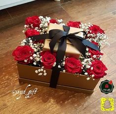 a box with red roses and baby's breath in it