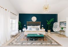 a bedroom with a green accent wall, white bedding and rugs on the floor