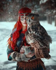 a woman with red hair is holding an owl in her hands while wearing a costume