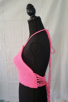 This crochet top is cotton candy pink in color. The strings tie around the neck as a halter top and interlace in the back. The adjustable ties can make the top fit looser if needed. If there is too much room around the waist, the ties may be tied more tightly. This yarn is stretchy and the lace-up back means it can fit various sizes. This particular top is recommended for sizes medium-large. This top does not have supportive cups or wiring built in. Summer Cross-tied Backless Halter Top, Pink Backless Halter Top For Vacation, Pink Backless Summer Top, Pink Backless Halter Top Summer Style, Pink Backless Halter Top For Beach, Pink Halter Neck Crochet Top For Beach, Pink Halter Neck Crop Top For Beach Season, Pink Sleeveless Crochet Top For Beach, Pink Beachwear Crop Top For Spring