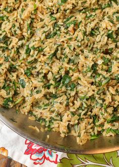 a large metal bowl filled with rice and spinach