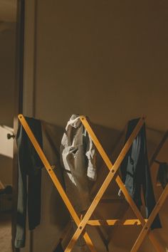 a chair with clothes hanging on it next to a coat rack and jacket hanger