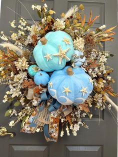 a wreath with blue pumpkins, starfish and flowers on the front door for fall