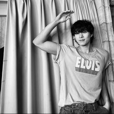 black and white photo of a young man leaning against a curtain