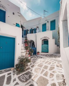 an alley way with blue doors and white buildings