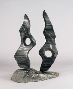 two metal sculptures sitting on top of a rock