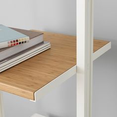 a stack of books sitting on top of a wooden table next to a white chair