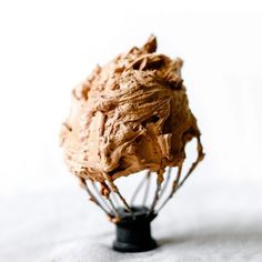 a whisk filled with chocolate frosting sitting on top of a table