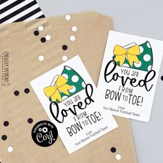 two tags with bows on them sitting next to each other in front of a brown paper bag