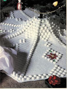 a crocheted christmas tree skirt with poinsettis on it