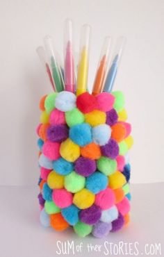 a multicolored vase filled with lots of pom - poms