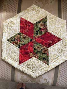 a person standing next to a quilted star on top of a couch with red and green flowers