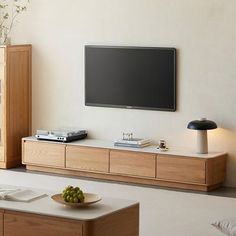 a flat screen tv mounted to the side of a wall next to a wooden cabinet