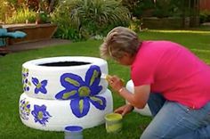 a woman is painting a flower pot in the grass