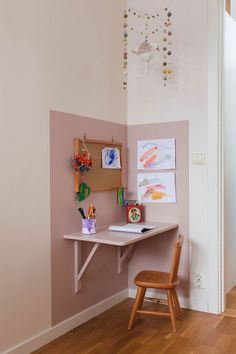 a desk and chair are in the corner of a room with pink paint on the walls