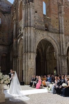 the bride and groom are getting married in front of an old building with stone arches