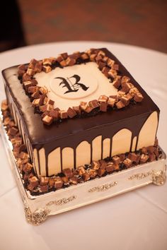 a square cake with chocolate and white frosting on a round tablecloth covered table