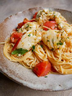 a white plate topped with pasta covered in shrimp and tomato sauce on top of a wooden table