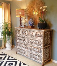 an ornate dresser in a living room with potted plants and lamps on the top