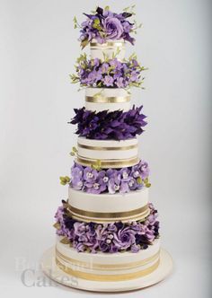 a multi tiered cake with purple flowers on top