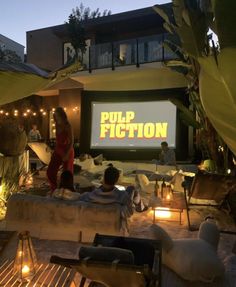 people sitting on couches in front of a movie screen at night with lights around them