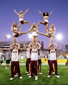 a group of cheerleaders standing on top of each other in front of a stadium