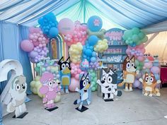 some cartoon characters are standing in front of balloons and streamers on the ground at a birthday party