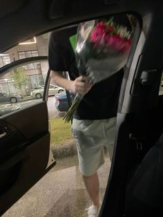 a man is holding flowers in his car