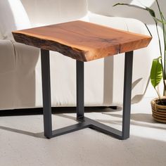 a wooden table sitting on top of a white couch next to a potted plant