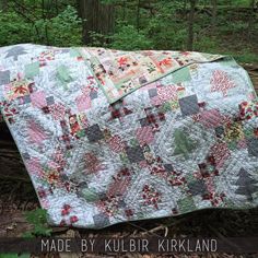 a quilted blanket sitting on top of a forest floor