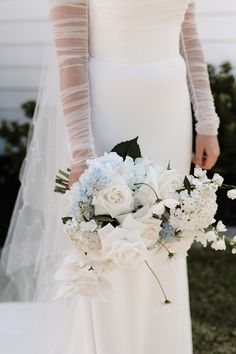 a bride holding a bouquet of white and blue flowers