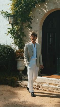 a man in a white suit is walking outside