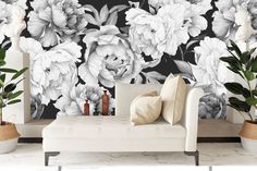 a white couch sitting in front of a black and white flower wallpapered room