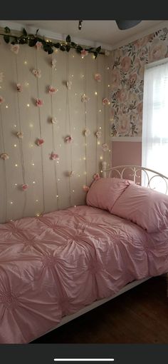 a bedroom with pink bedding and string lights