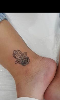 a small hamsa tattoo on the back of a woman's leg and foot