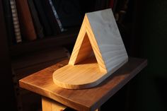 a wooden object sitting on top of a table next to a book shelf with books in the background