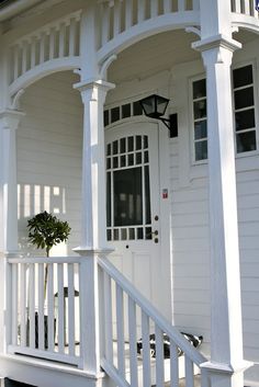 a white house with a small tree in the front yard and stairs leading up to it