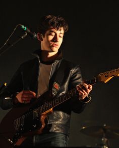 a man holding a guitar while standing next to a microphone