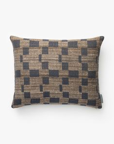 a brown and black checkered pillow sitting on top of a white wall