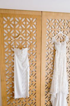 two white dresses hanging on wooden panels