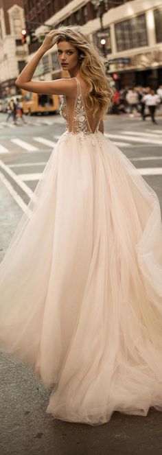 a woman in a wedding dress is standing on the street